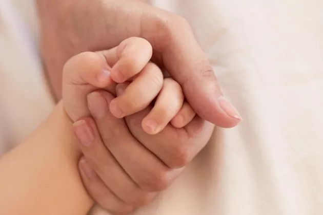 Förälder håller ett barns hand. Foto.